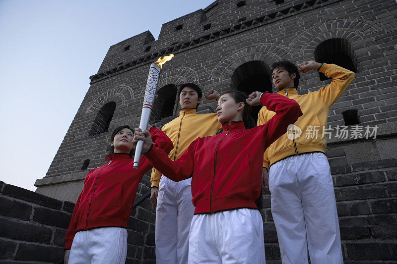 四位身穿运动服的年轻人在奥运火炬前宣誓