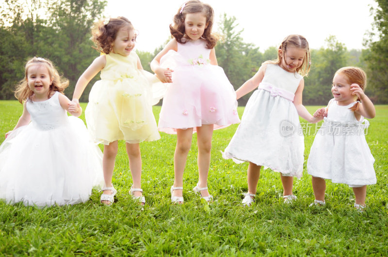 五个穿着裙子的快乐小女孩在外面跳