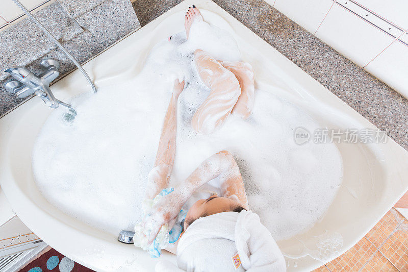 年轻漂亮的女孩在浴缸里洗澡。