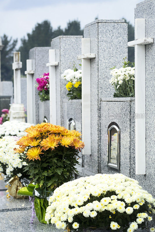近距离的十字架和鲜花在墓地。