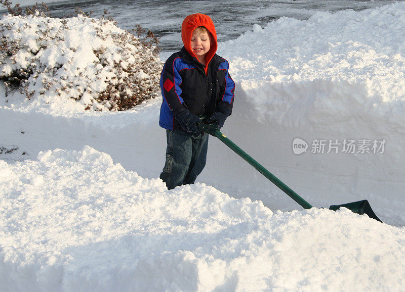 快乐的蹒跚学步的男孩与雪铲