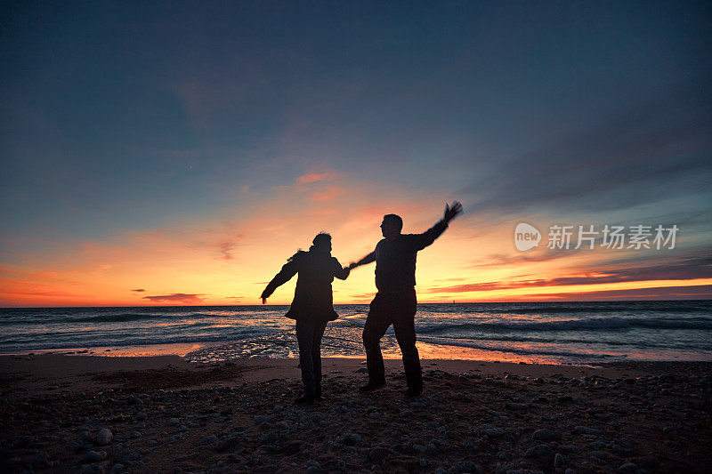 一对老年情侣在夕阳下在海边跳舞