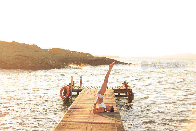 日落时分，年轻女子在码头上锻炼