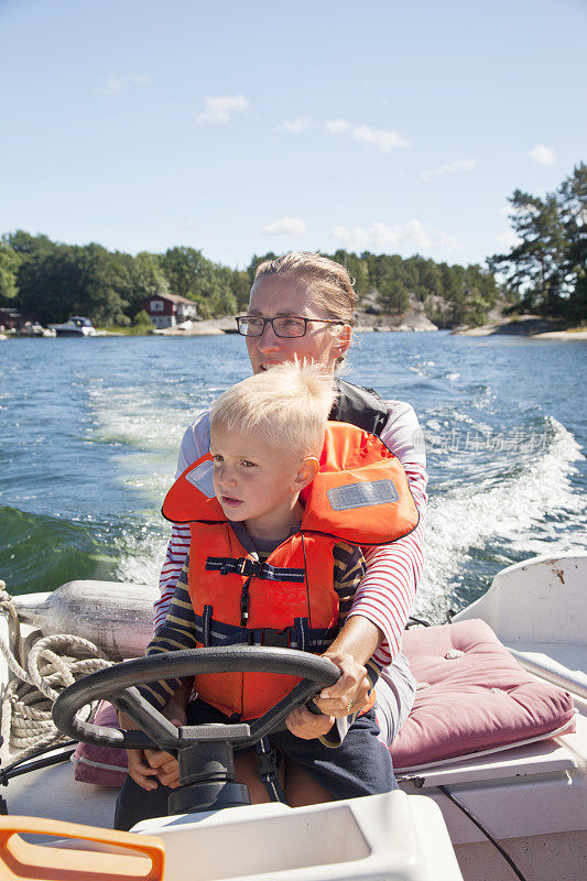 母亲和儿子穿着救生衣在一艘小船上