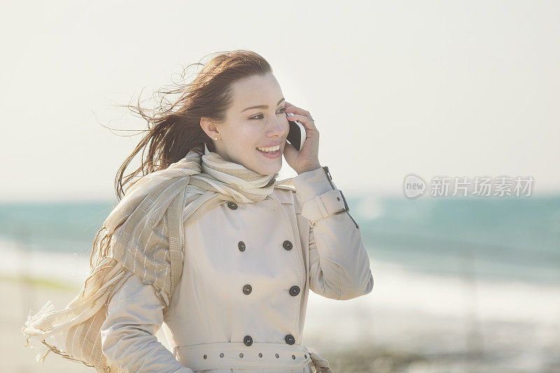 一名年轻女子在地中海海滩上使用手机