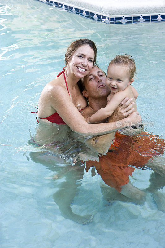 快乐的家庭和小男孩在游泳池里玩