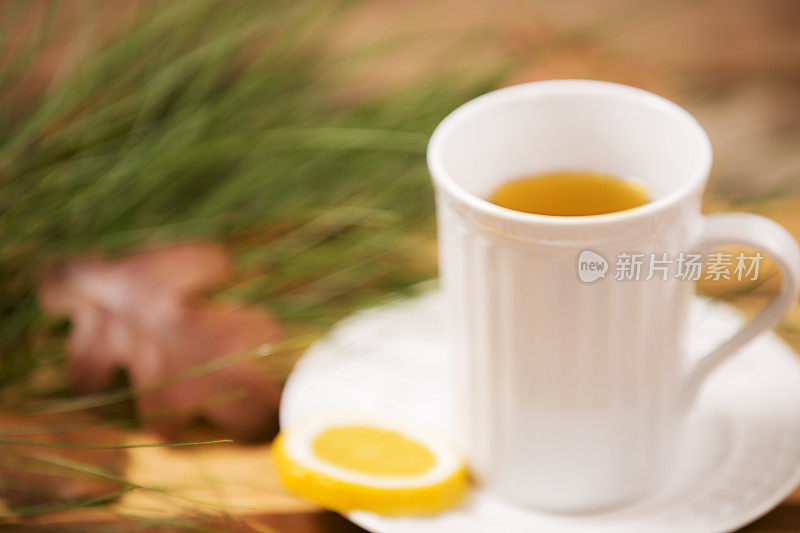 凉茶，白色杯子。落叶，松枝。木制的桌子。