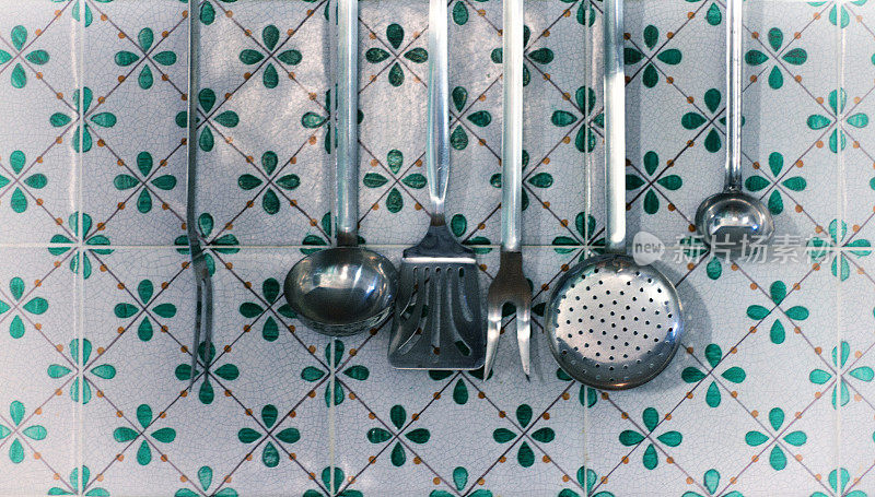 挂在意大利瓷砖上的金属厨房用具