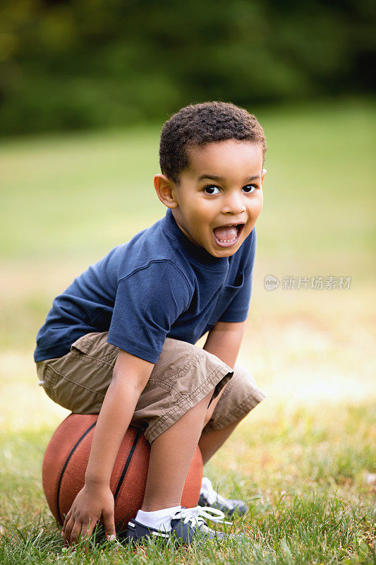 非裔美国男孩在户外坐在篮球上