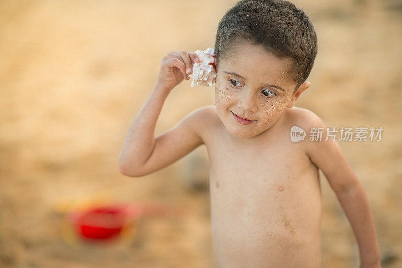 在夏威夷热带海滩上听贝壳的小男孩