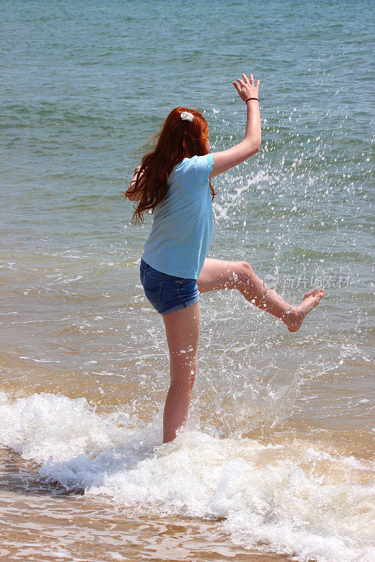 一个女孩在海滩上玩耍,溅起水花,在大海里嬉戏