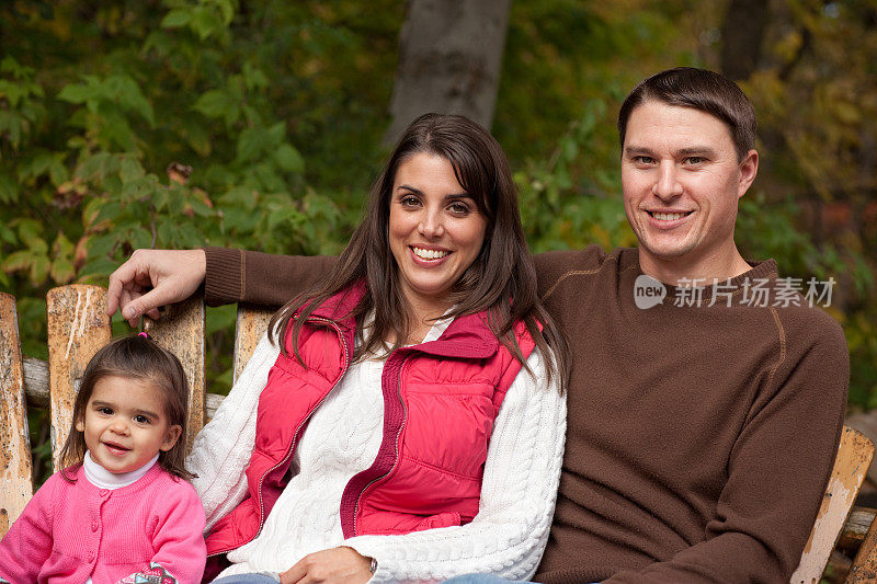 幸福的三口之家坐在秋天的树林里