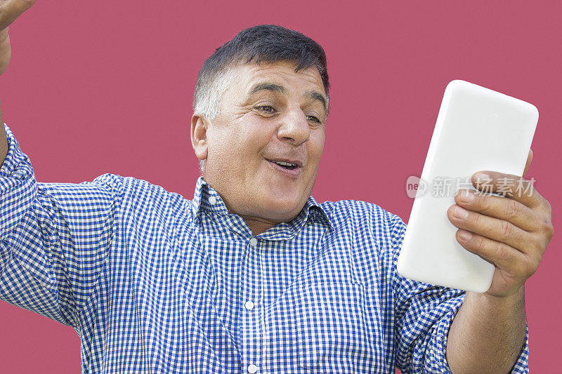低角度的快乐成熟的男人看着数字平板电脑与惊讶的表情在彩色的背景