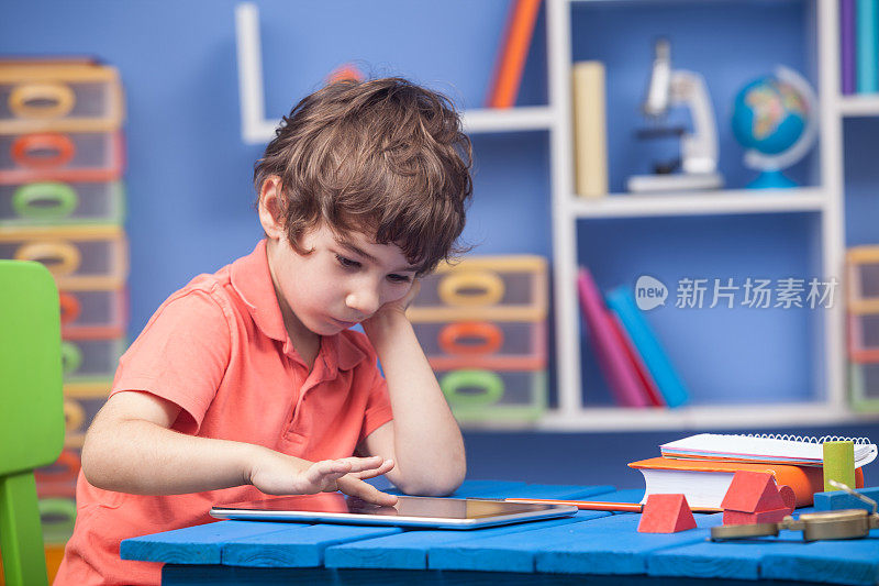 小男孩在使用数字平板电脑的同时学习编程