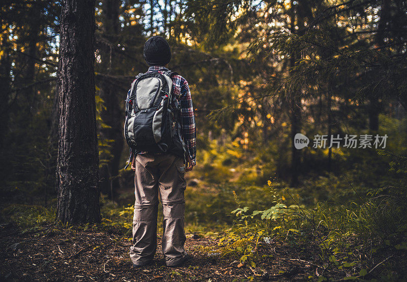 日落时分，可爱的男孩独自在森林里徒步旅行