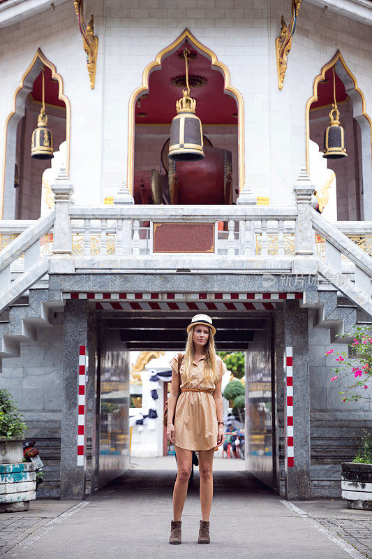一名女子走在曼谷的街道上，探索寺庙区域