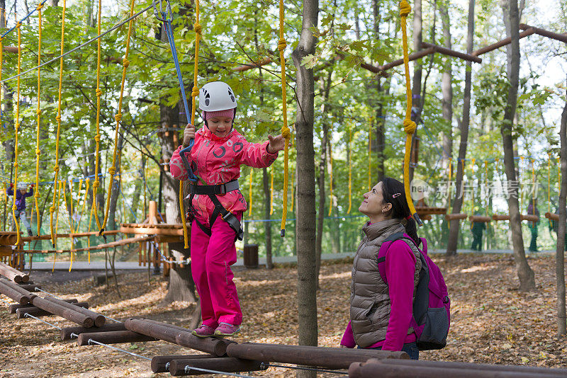 十几岁的女孩有乐趣在绳索课程冒险公园。Zipline为孩子。