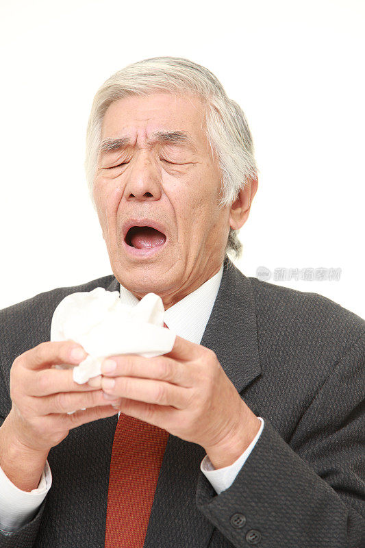有过敏症状的日本资深商人对着纸巾打喷嚏