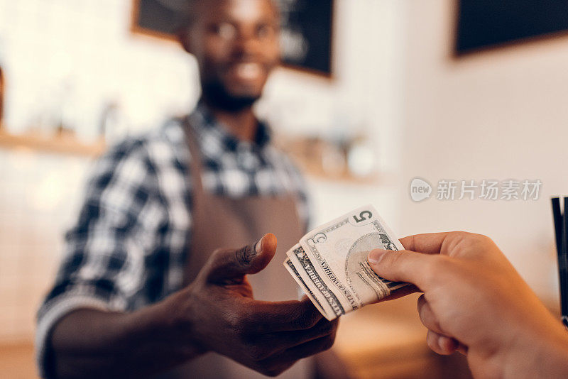 非裔美国咖啡师在咖啡馆柜台接受现金付款的选择性焦点