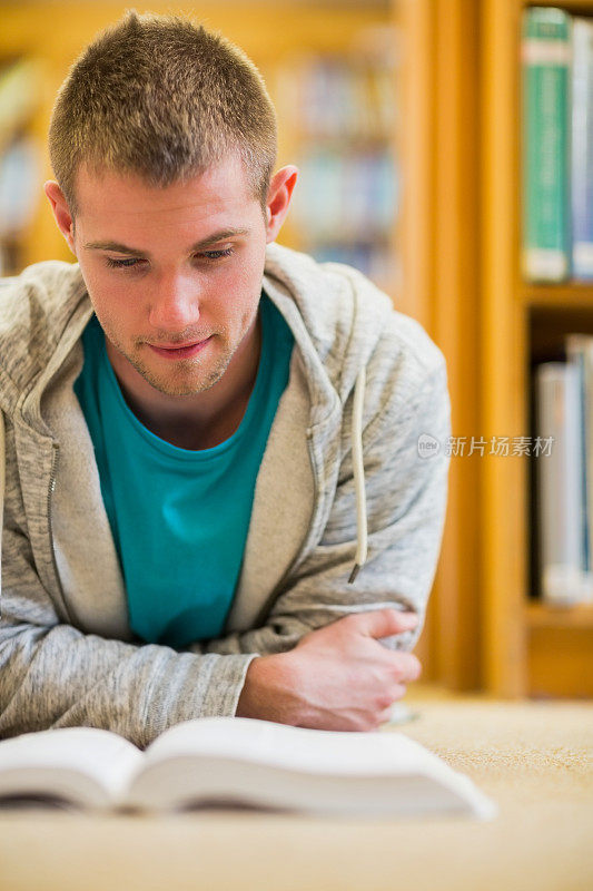 男学生在学院图书馆的地板上看书