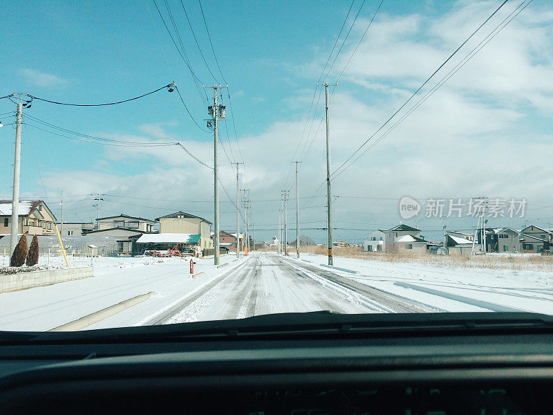 汽车在日本村庄的雪覆盖的道路上行驶