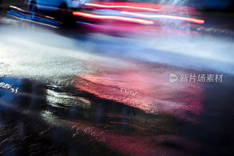 模糊的汽车在运动，溅着雨水在夜间行驶