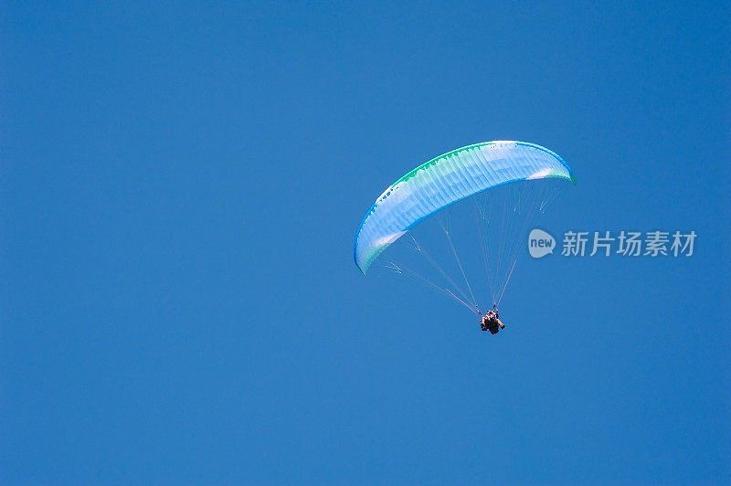 在蓝天的背景下独自飞行的滑翔伞。
