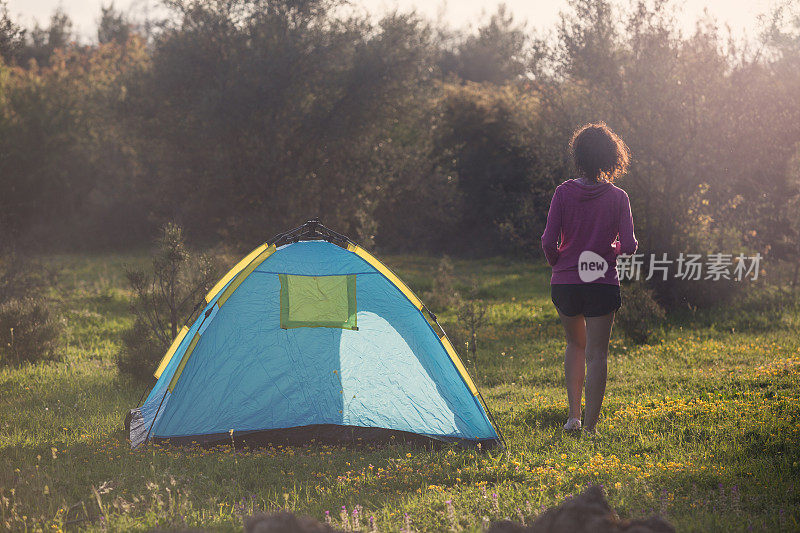 一个成年妇女站在露营帐篷前的春天