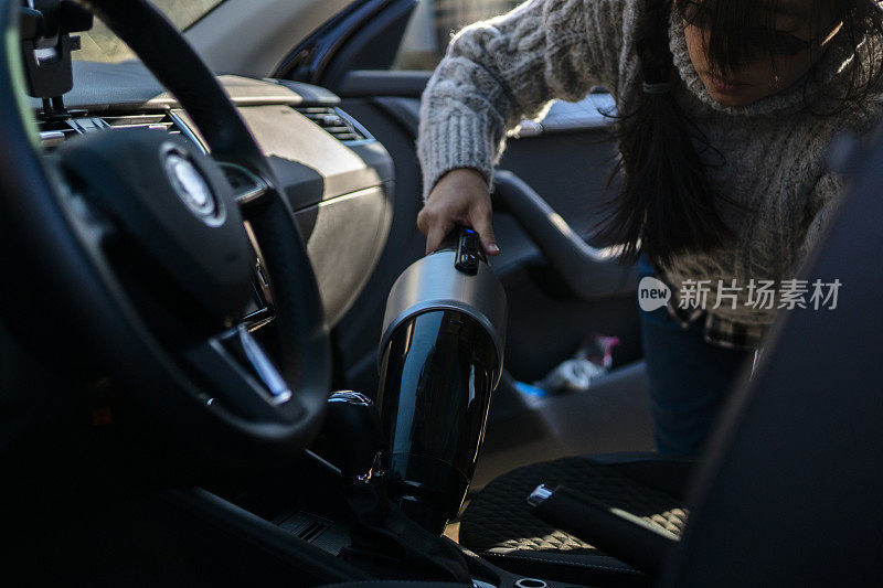 女孩用便携式清洁器清洗汽车