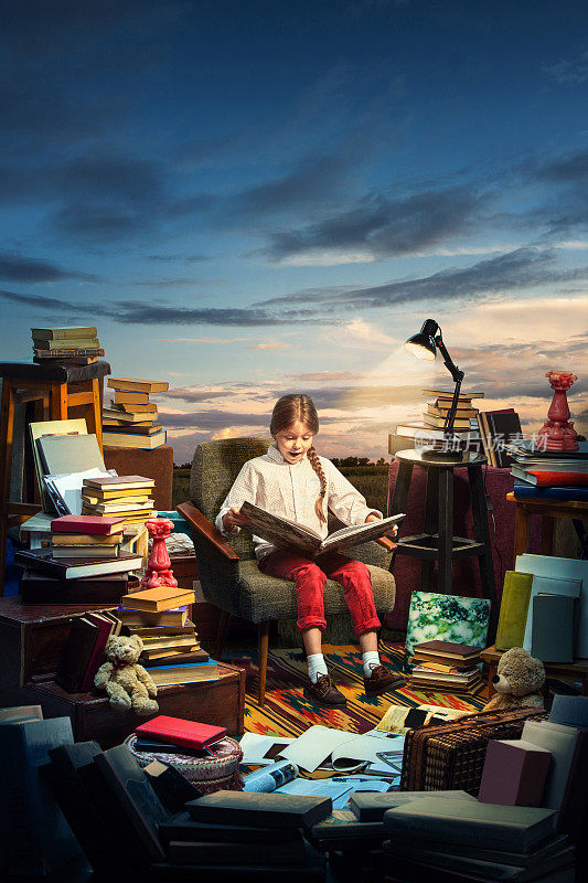 小女孩坐在打开的书上。童年的梦想、创造和教育理念。不知道的世界。抽象拼贴画