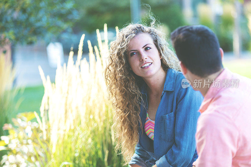 男和女年轻的大学年龄的朋友在一个大学公共区域的户外进行有趣的谈话