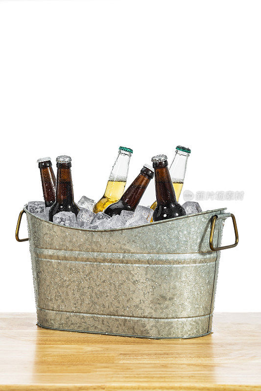 木桌上放着一个镀锌的浴盆，冰上放着各种各样的啤酒瓶