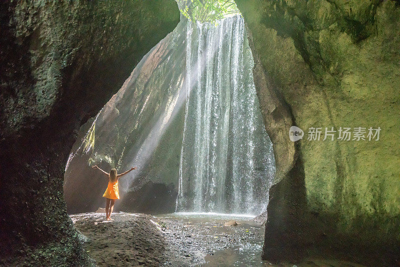 在巴厘岛的热带雨林中，旅行的年轻女子张开双臂拥抱大自然的美丽。人们以自然为旅游理念。