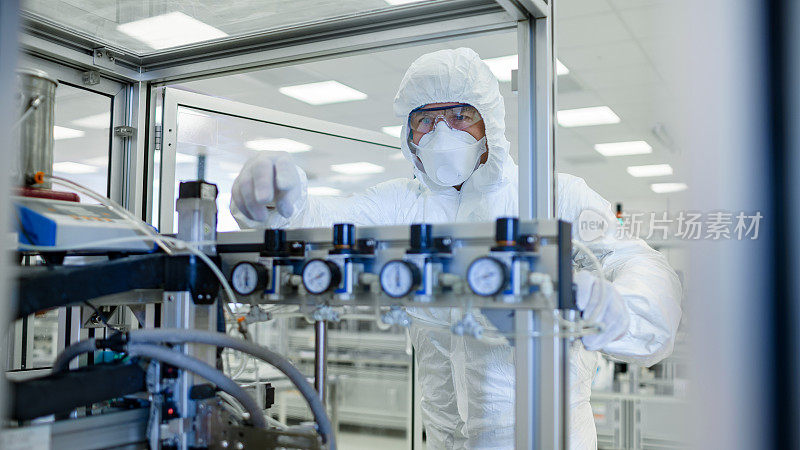 在制造设施拍摄的科学家在无菌防护服在现代工业3D打印机器上工作。制药，生物技术制造工艺。从里面。
