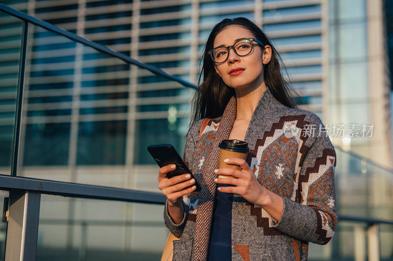 迷人的女人一边喝咖啡一边发短信