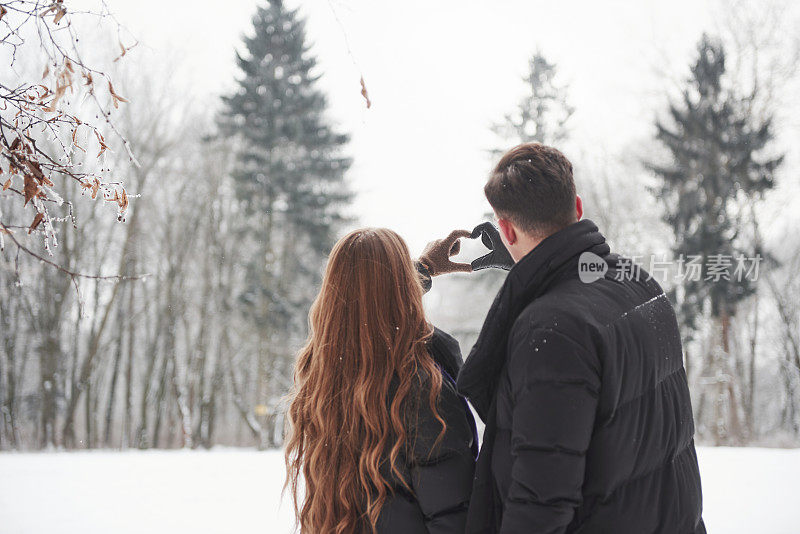 爱要穿越距离。美丽的年轻夫妇有美好的时光一起在雪山森林