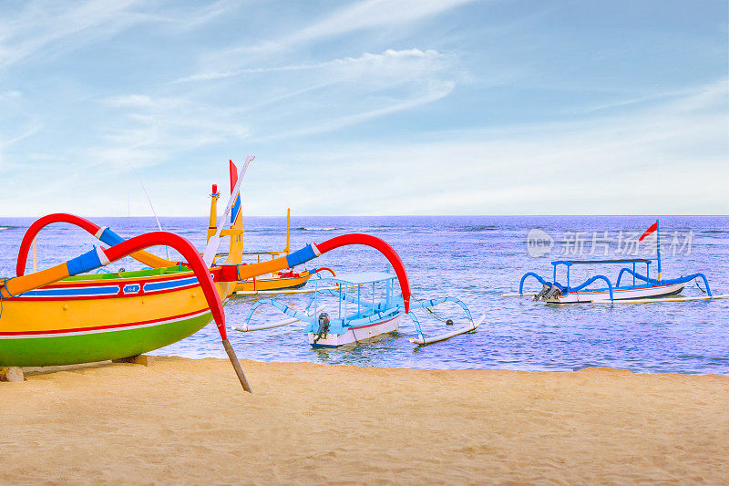 印度尼西亚萨努尔海滩上的巴厘岛传统渔船的全景图。美丽的印度尼西亚热带海滩与蜘蛛船。热带夏季概念背景。