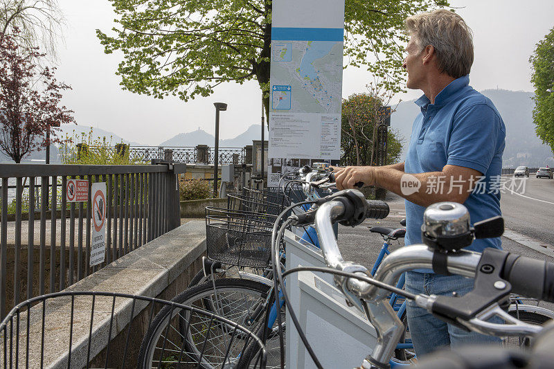 一个成熟的男人从科莫湖的自行车架上挑选一辆自行车