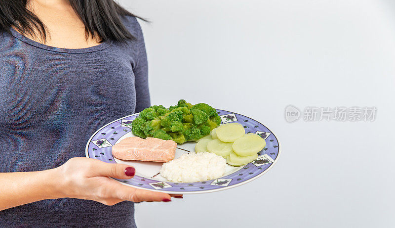 女营养学家拿着装有蔬菜和鸡肉的盘子