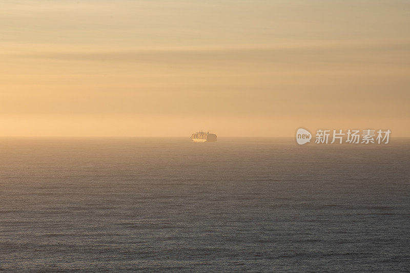 货运船驶进地平线-美丽的日落海背景橙色和蓝色