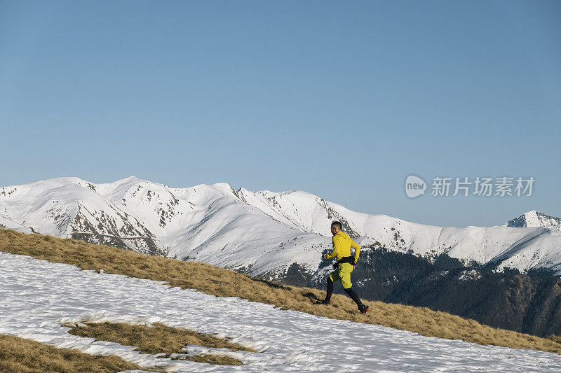 黎明时分，一名徒步运动员爬上雪山的山脊