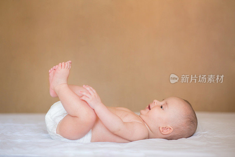 新生儿仰面躺着，微笑着发现自己的双脚