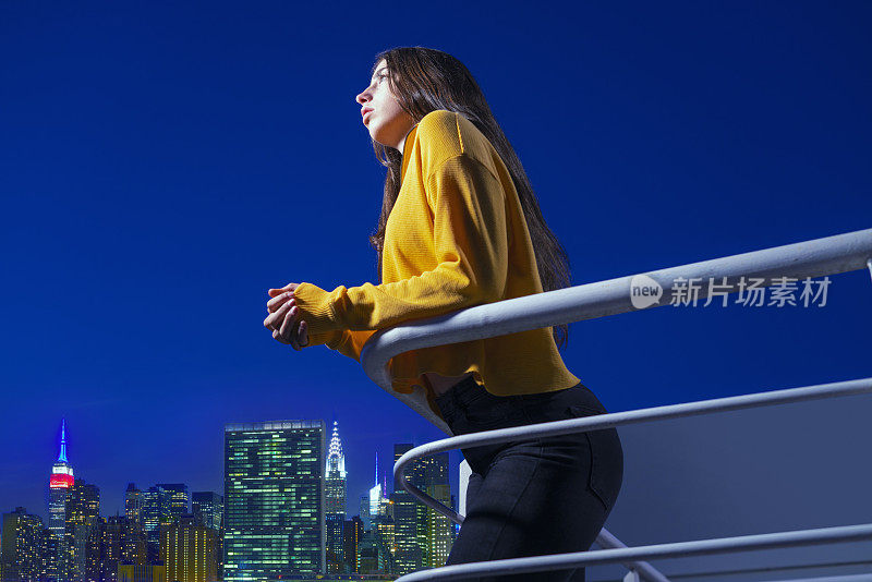 少女在家里的阳台上看日落蓝色的小时到纽约曼哈顿天际线