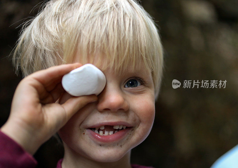 一个小男孩在一次徒步旅行中，他的眼睛旁边放着一只棉花糖。