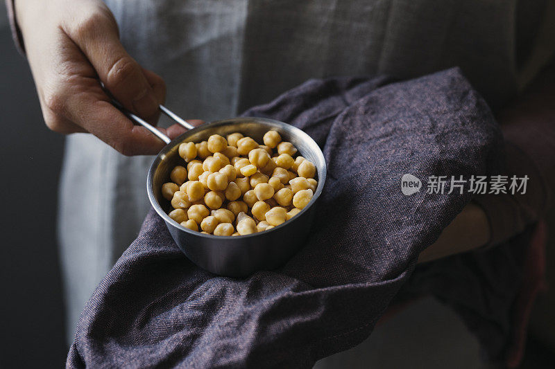 一个匿名女人的手拿着在量杯里煮熟的鹰嘴豆