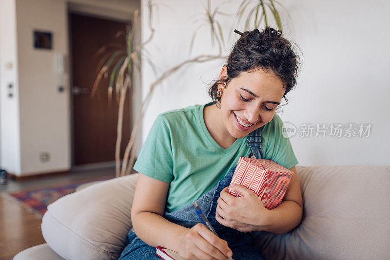 一名年轻女子正在准备一份礼物和一条她想送给某人的信息