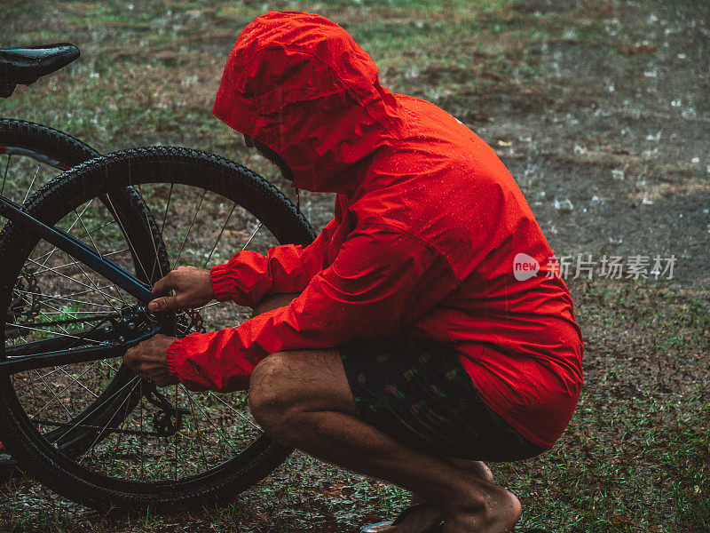 一名男子在暴雨中修理山地车