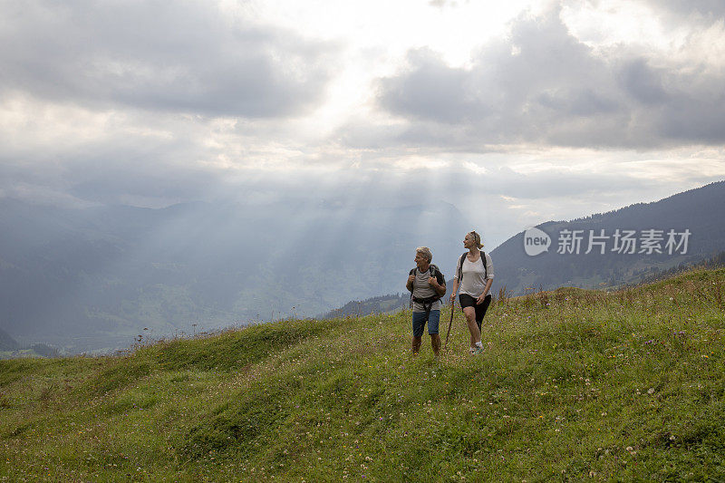 日出时分，一对成年夫妇徒步穿过高山草甸