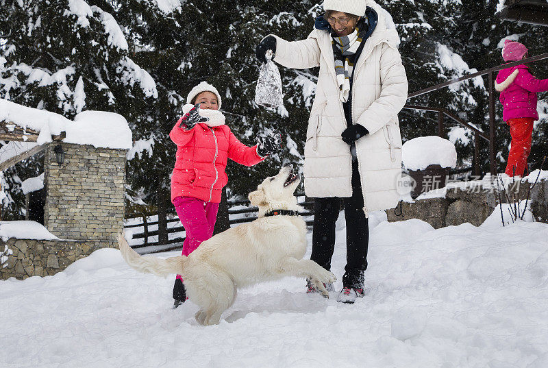 小女孩们，一个老妇人和一条狗在雪地里玩耍