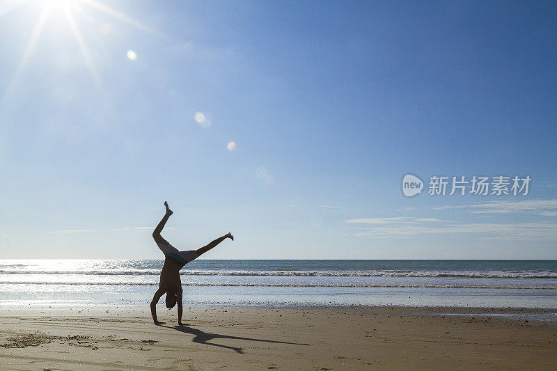 在海滩上做瑜伽和杂技体操的男子体操运动员